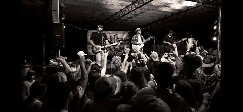 Black and white crowd shot with hands up as Shackelford Lane plays under a pavilion