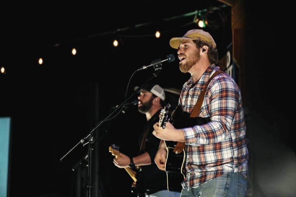 Will and Reid Shackelford in profile on stage under string lights