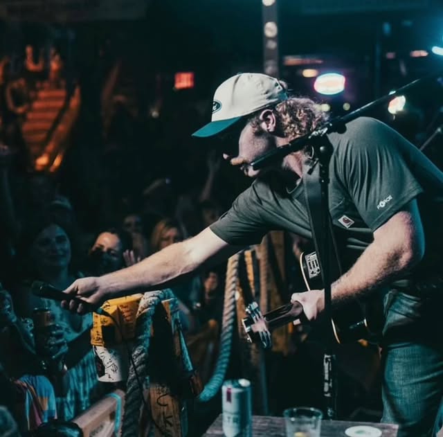 Performer extending the microphone to fans at the front of the stage
