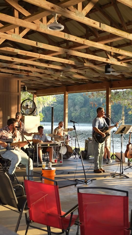 Shackelford Lane full band performing outdoors under a wooden pavilion by the water